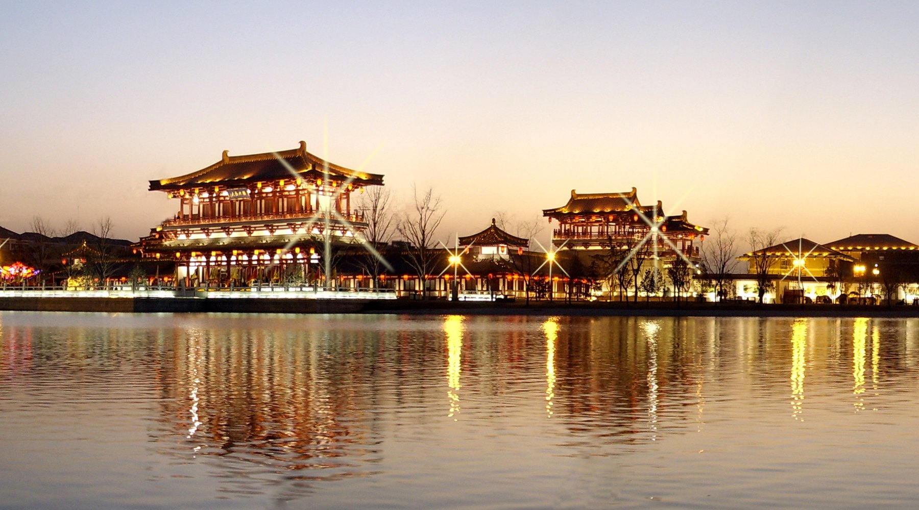 Tang-style pavilions lit up at night beside the water in Xi'an